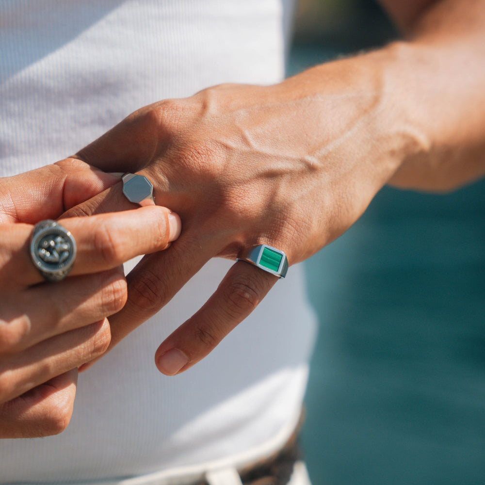 Two hands with rings on fingers against a blurred natural background