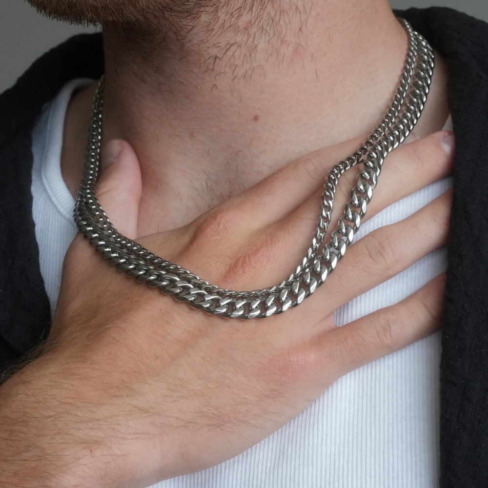 Close-up of a person wearing a silver chain necklace with a hand adjusting it.