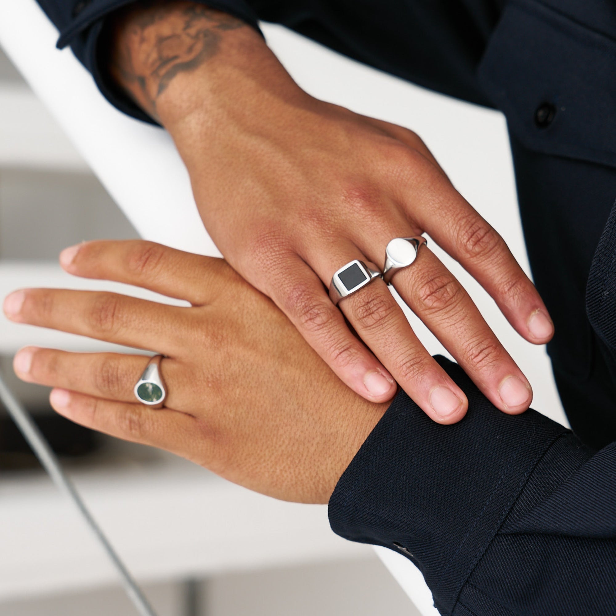 Close-up of two hands wearing rings with a blurred background