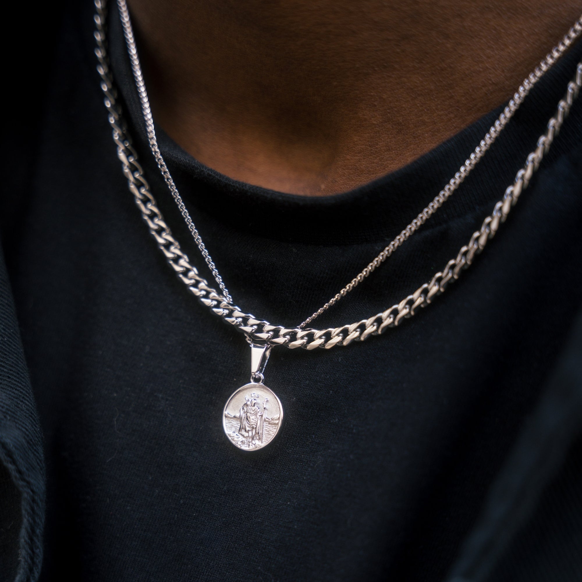 Two necklaces with pendants on a black shirt