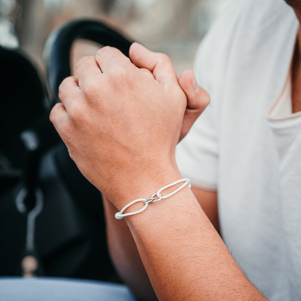 Close-up of two hands holding each other with a silver bracelet on one wrist.