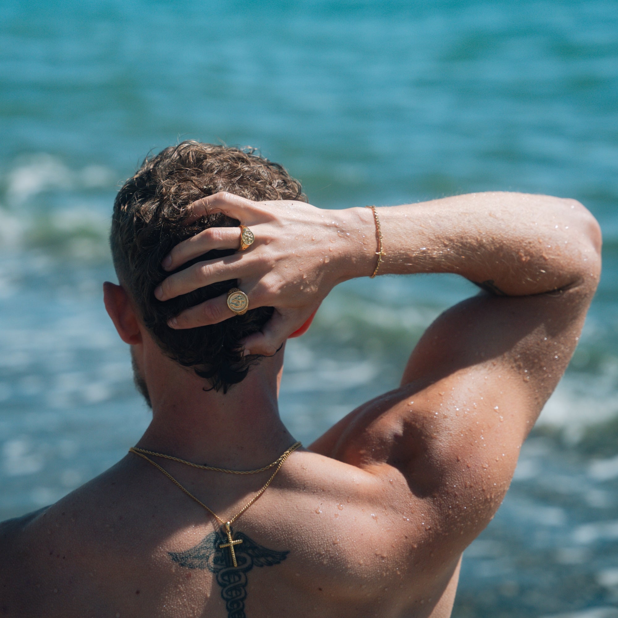 Man with a tattoo on his shoulder standing by the ocean