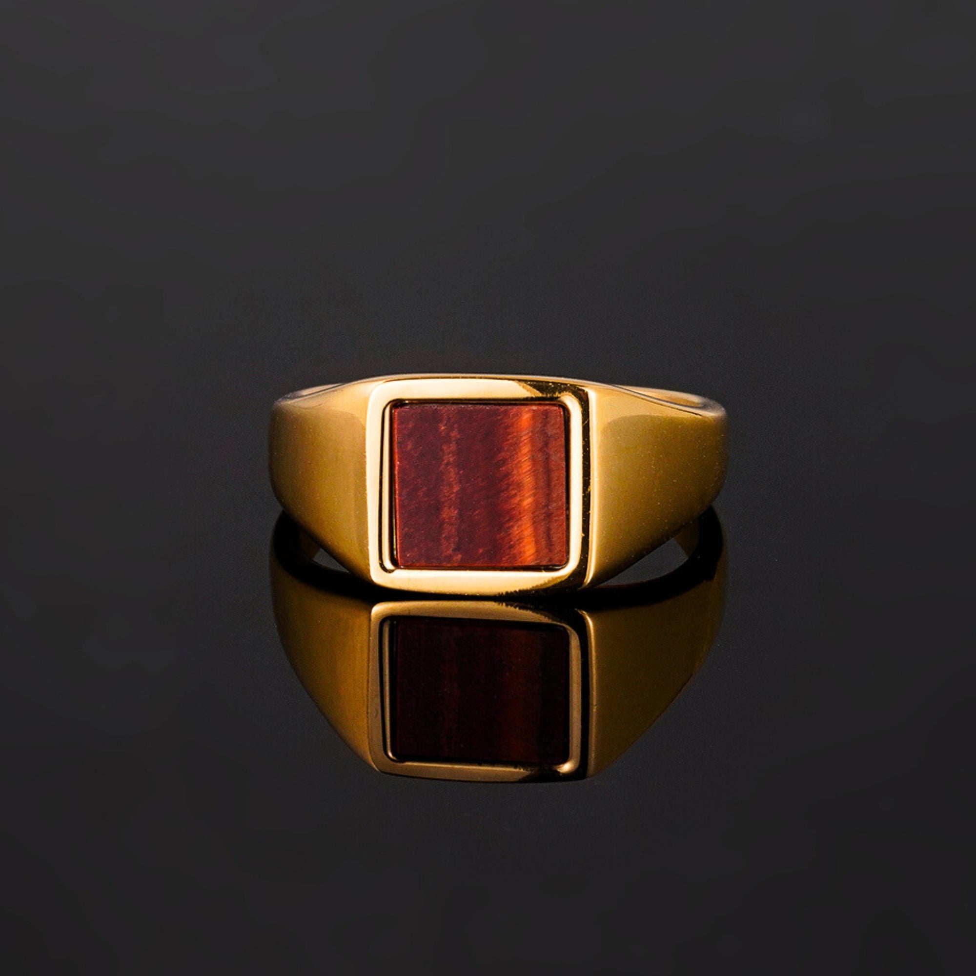 Gold ring with a red stone on a black background