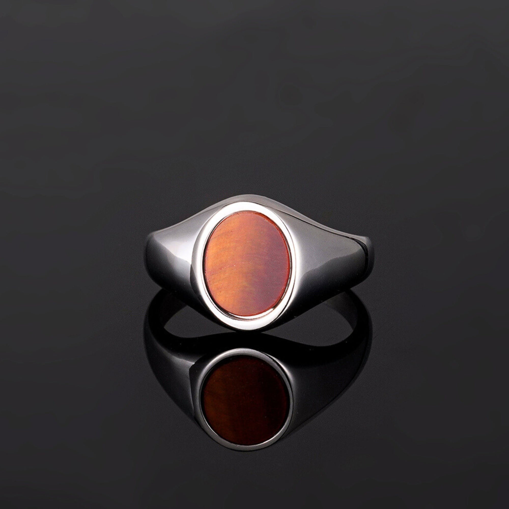 Silver ring with a brown oval stone on a black background