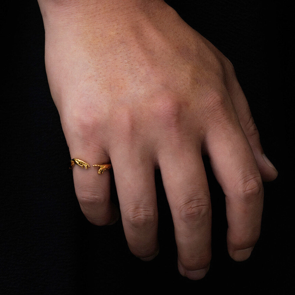 Hand wearing a gold ring on a black background