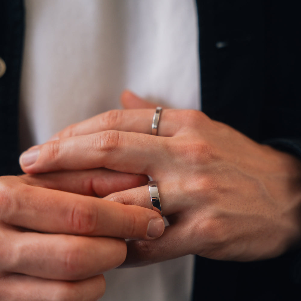 Close-up of two hands with silver rings on a blurred background