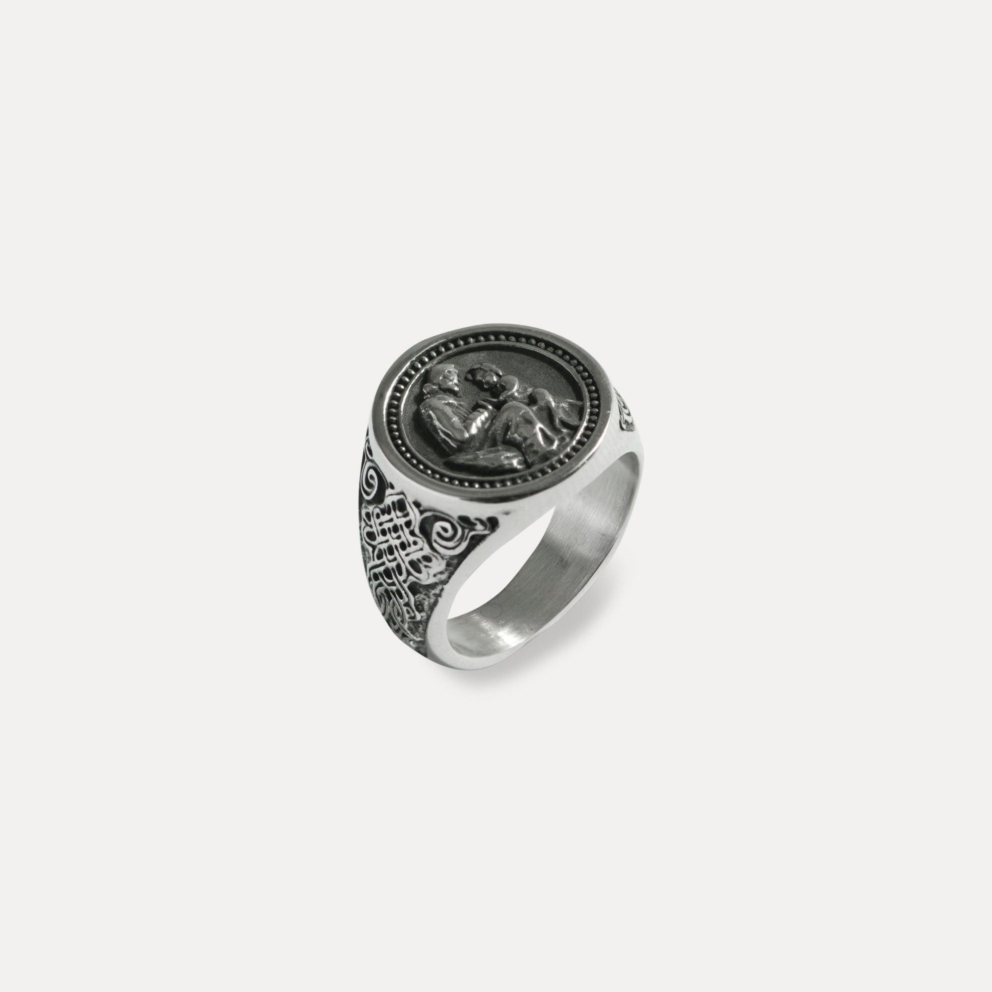 Silver ring with intricate design on a light gray background