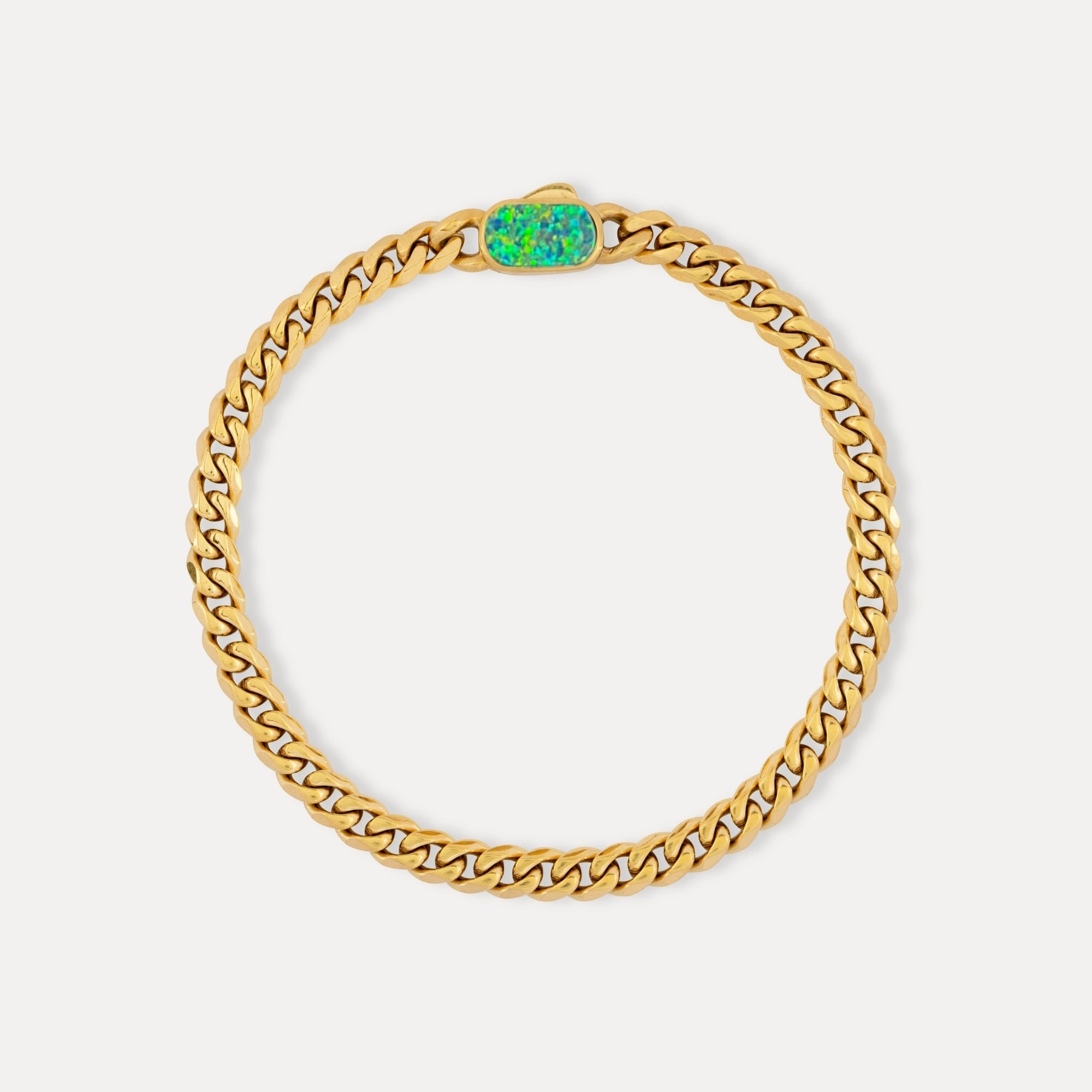 Gold chain bracelet with a green gemstone on a white background