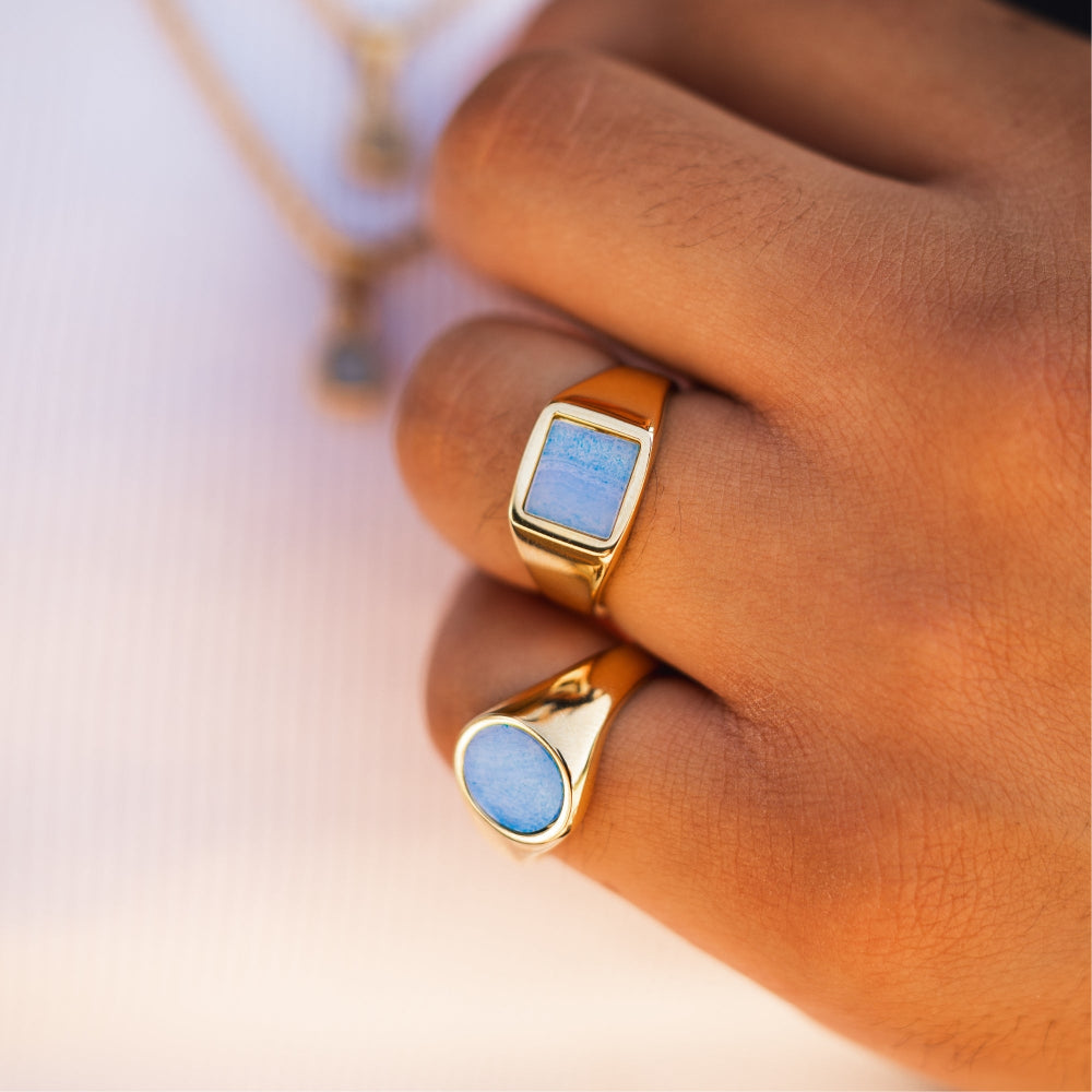 Gold rings with blue stones on a hand against a blurred background