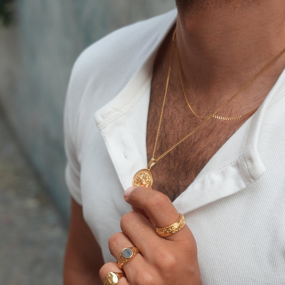 Person wearing gold necklaces and rings with a blurred background
