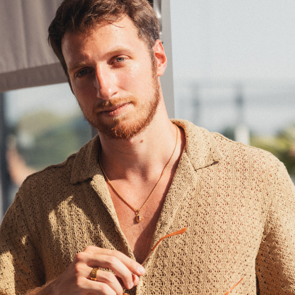 Man wearing a beige sweater with a blurred outdoor background