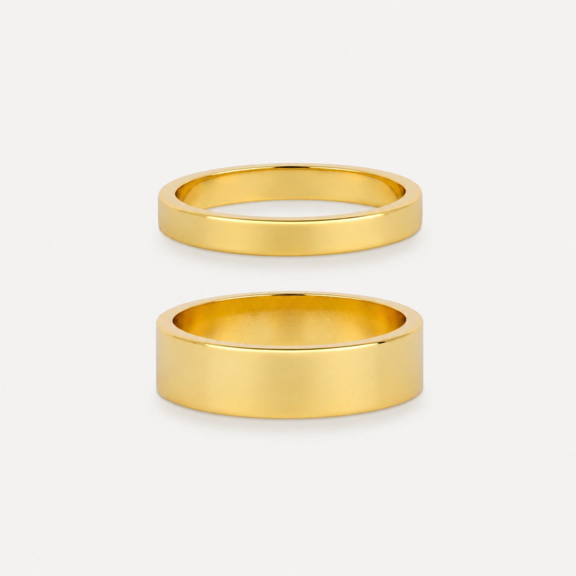 Two gold rings on a light gray background