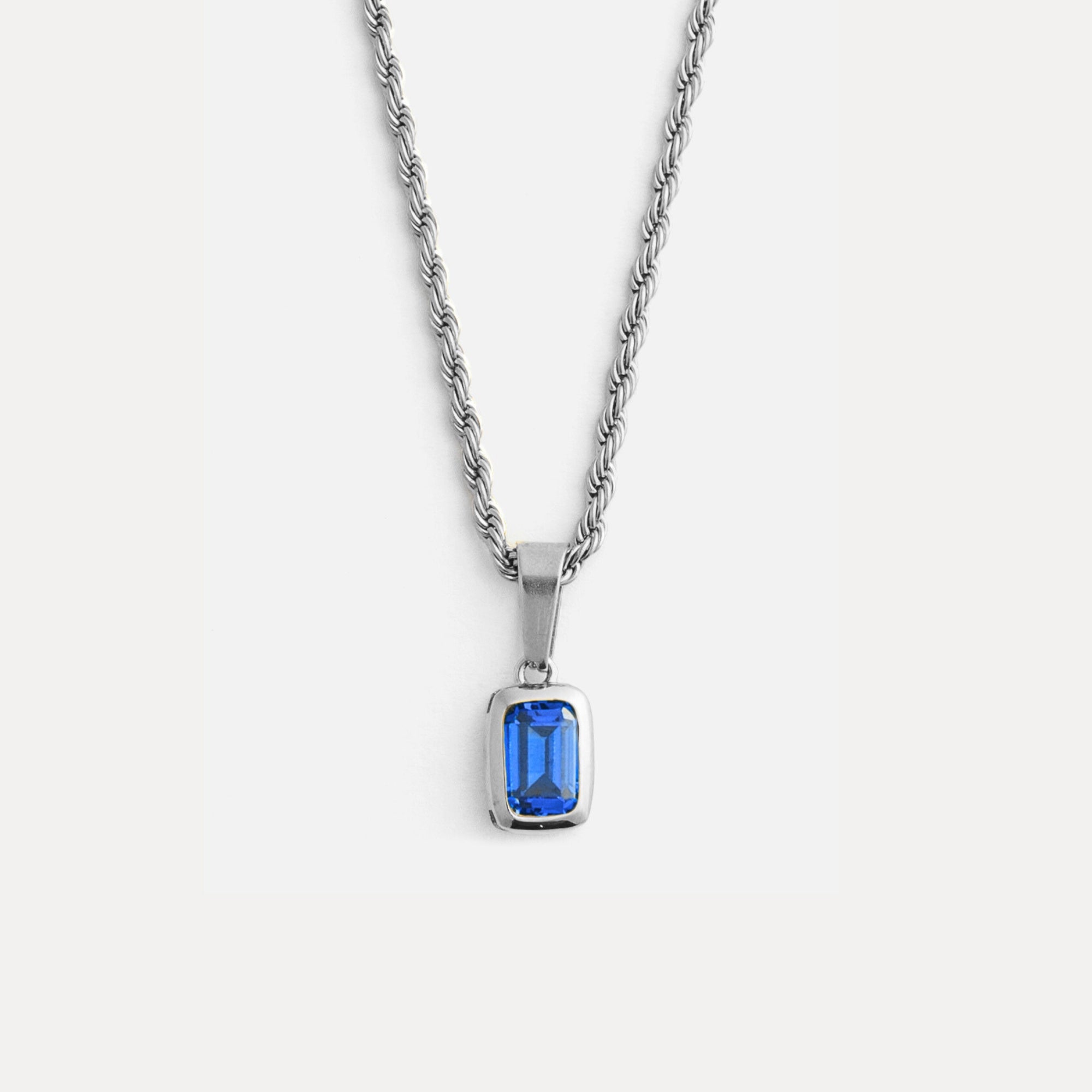 Silver necklace with a blue gemstone pendant on a white background