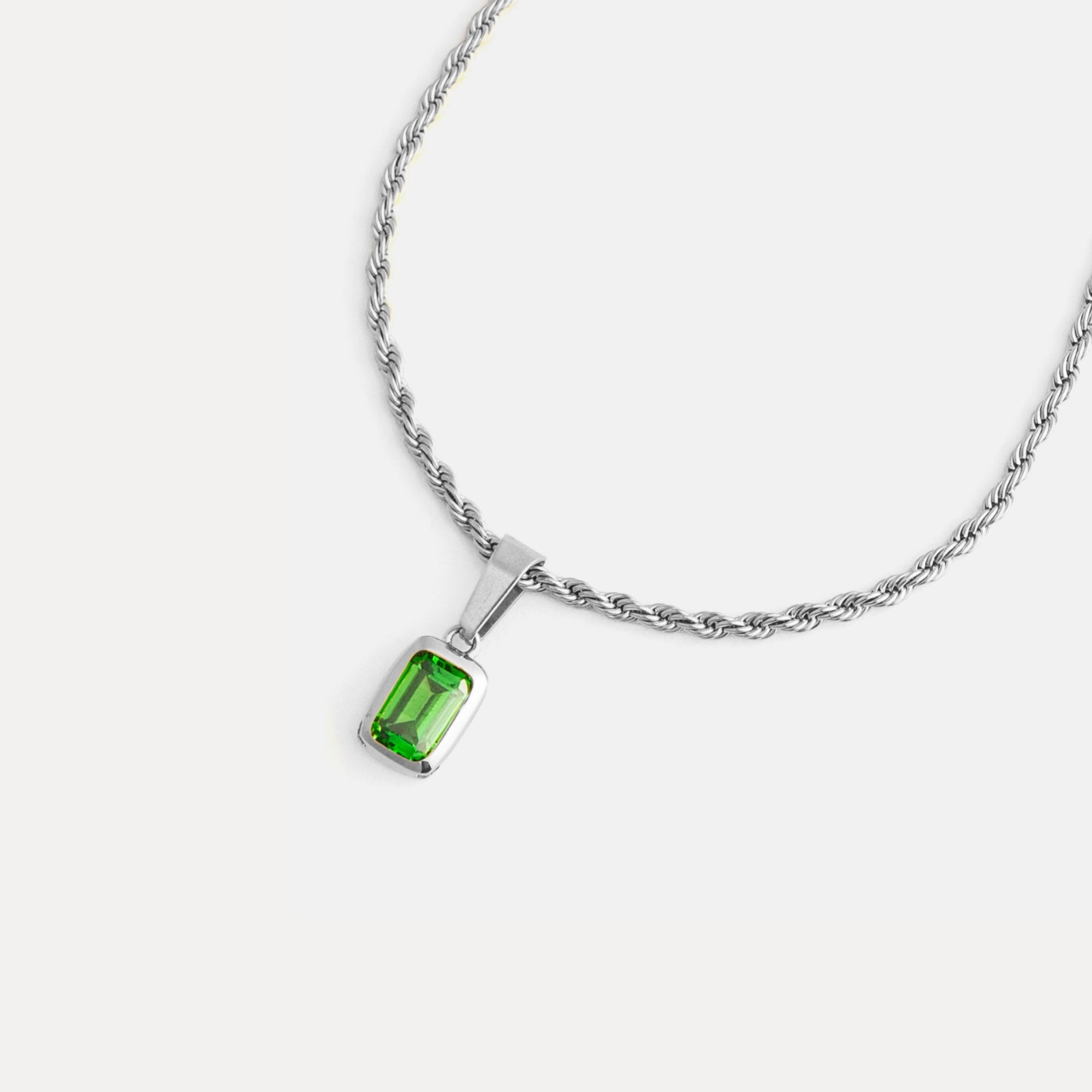 Silver necklace with a green gemstone pendant on a white background