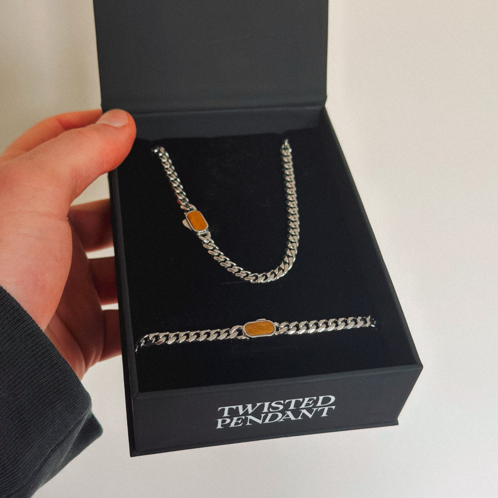 Silver chain necklace with orange accents in a 'Twisted Pendant' box.