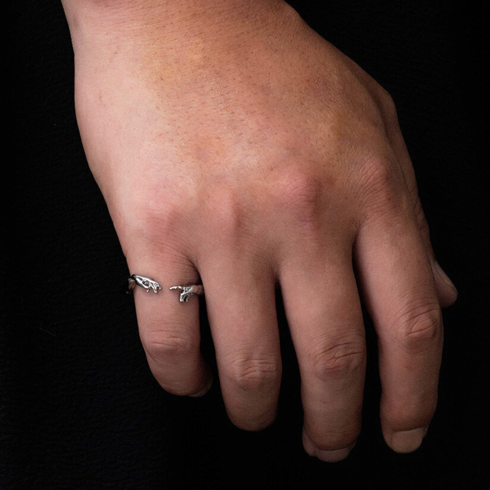 Hand wearing a silver ring on a black background