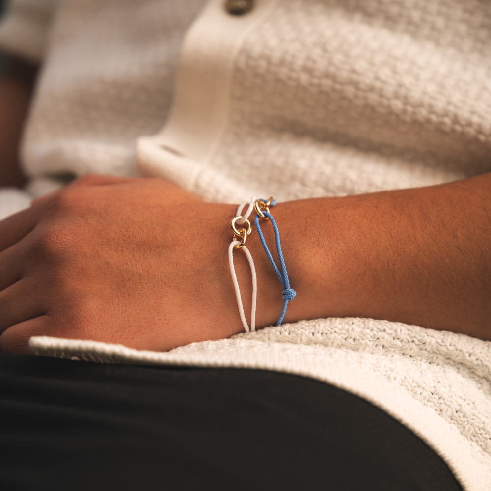 Close-up of a wrist wearing two bracelets on a neutral background