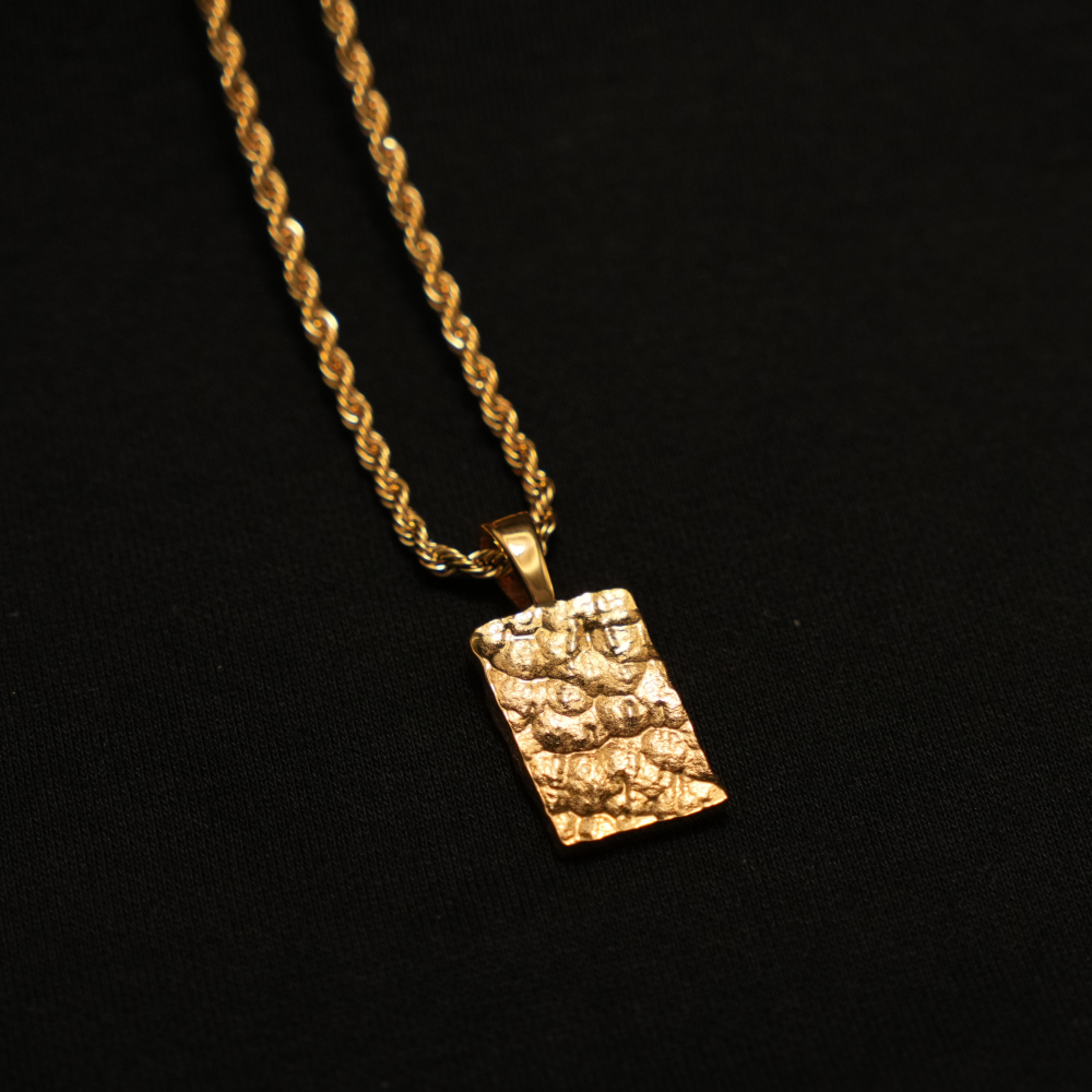 Gold pendant with textured design on a black background