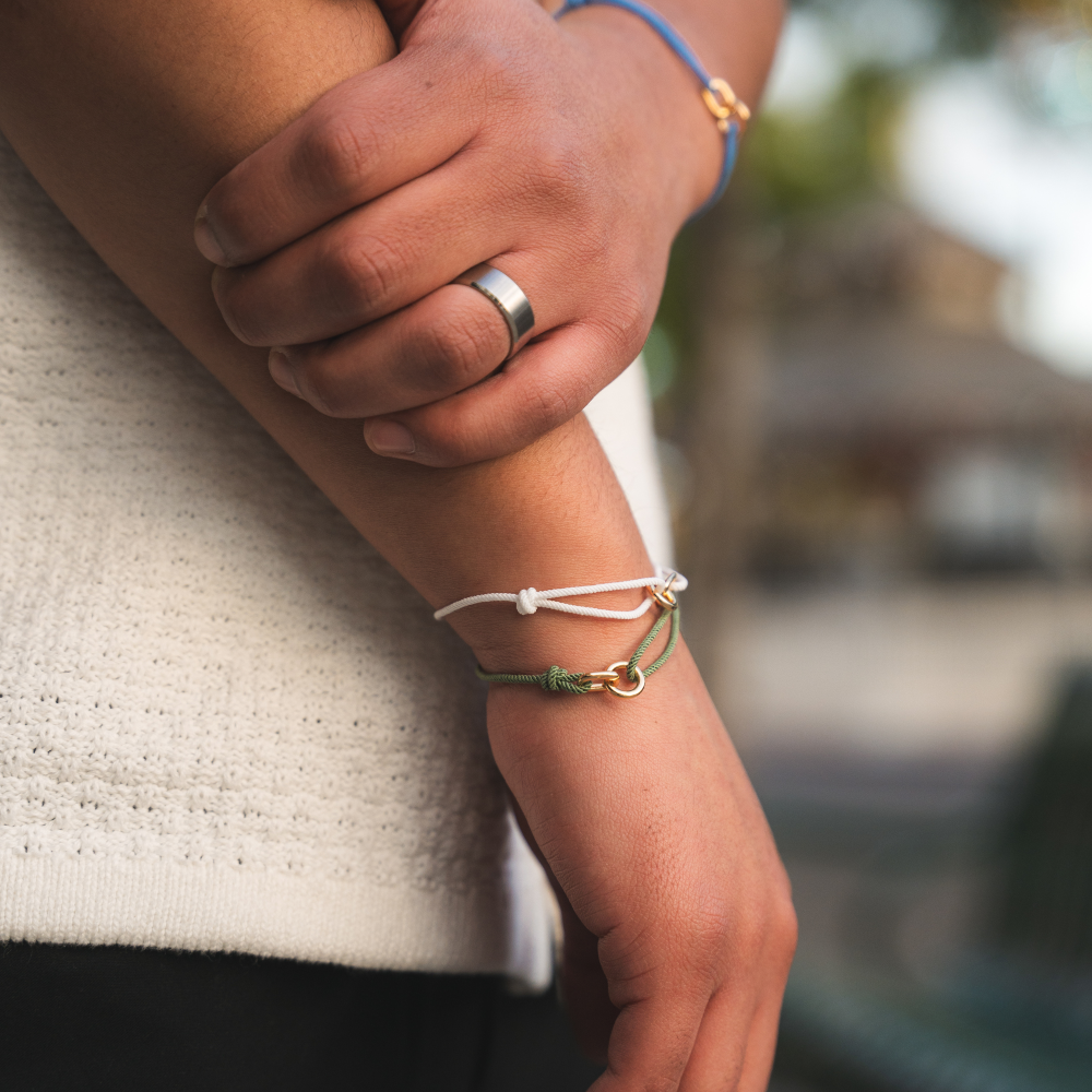 Close-up of a person's arm with bracelets and a ring, blurred background