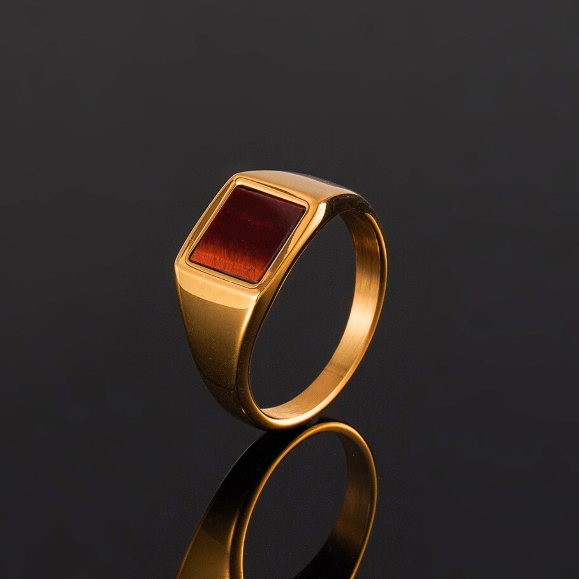 Gold ring with a red stone on a black background