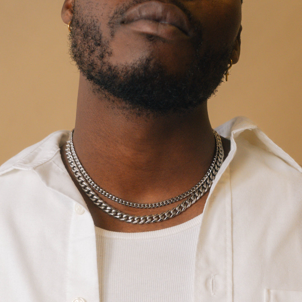Man wearing a white shirt and silver chain necklace against a beige background