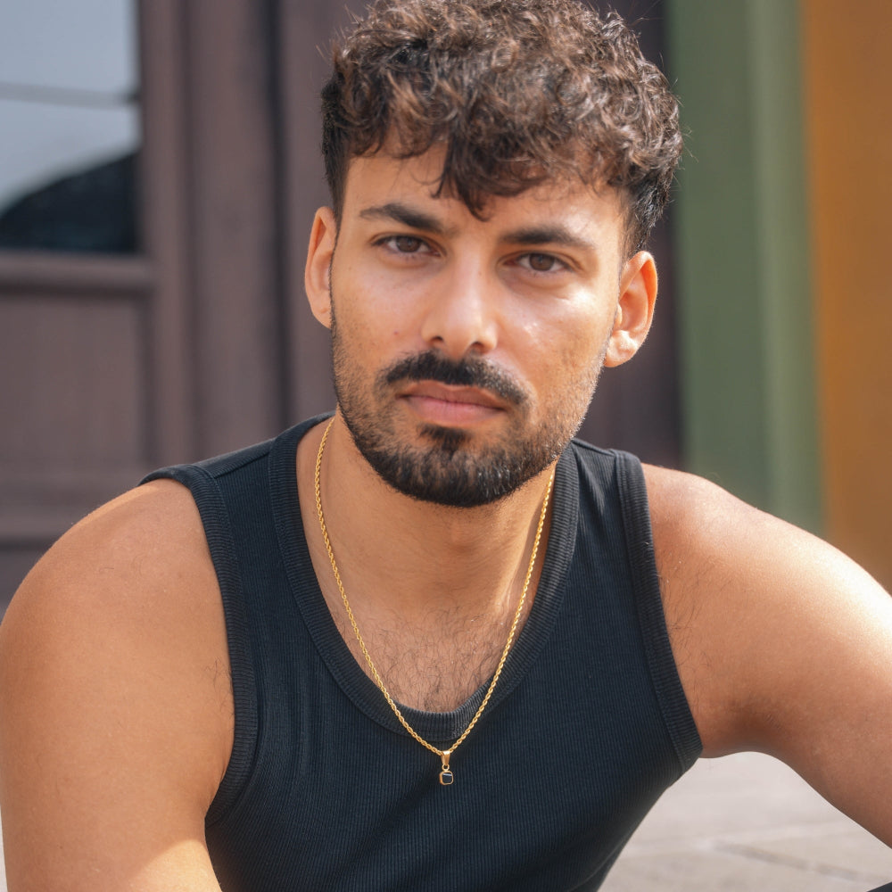 Man wearing a black tank top and gold necklace outdoors