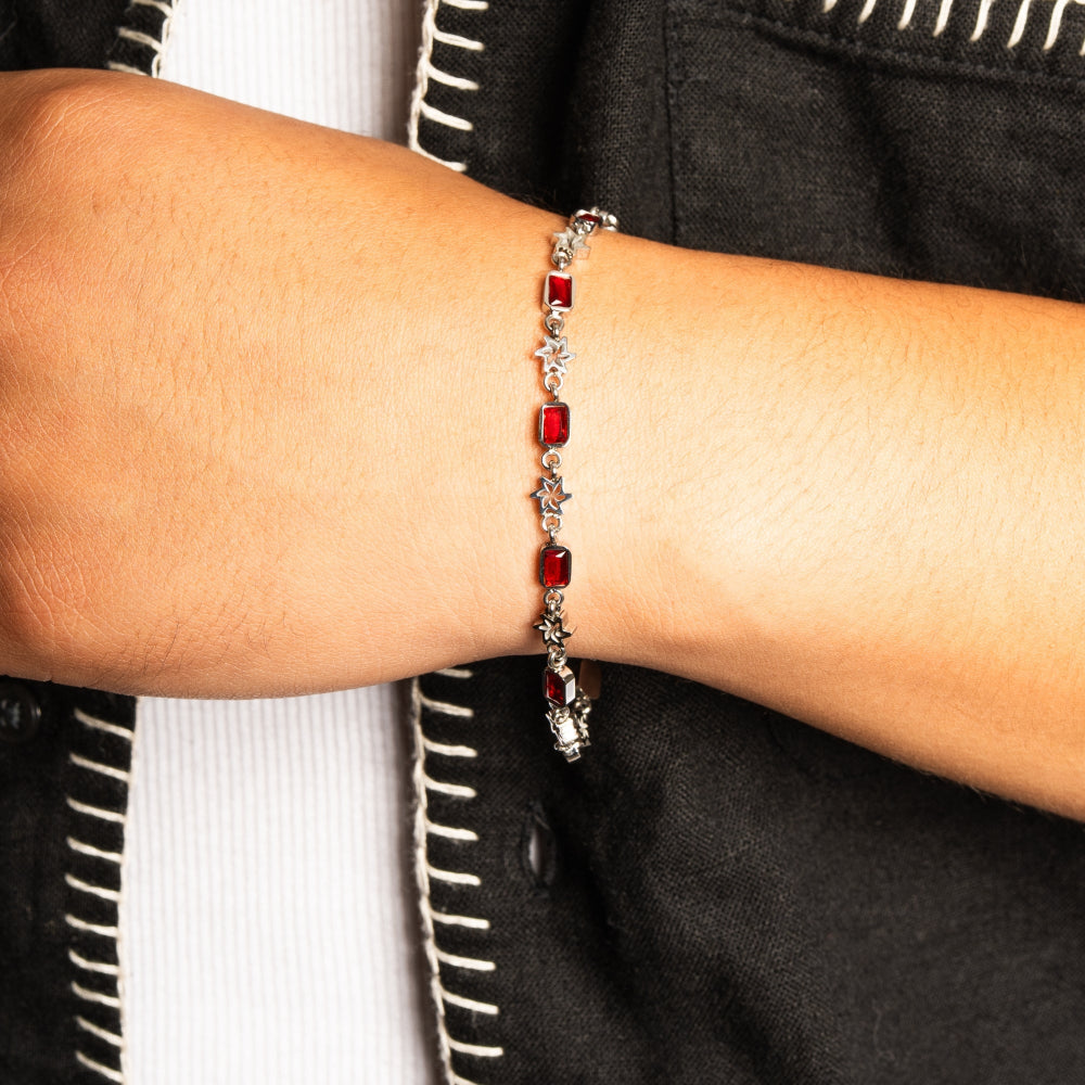 Bracelet with red beads on a person's wrist against a dark background