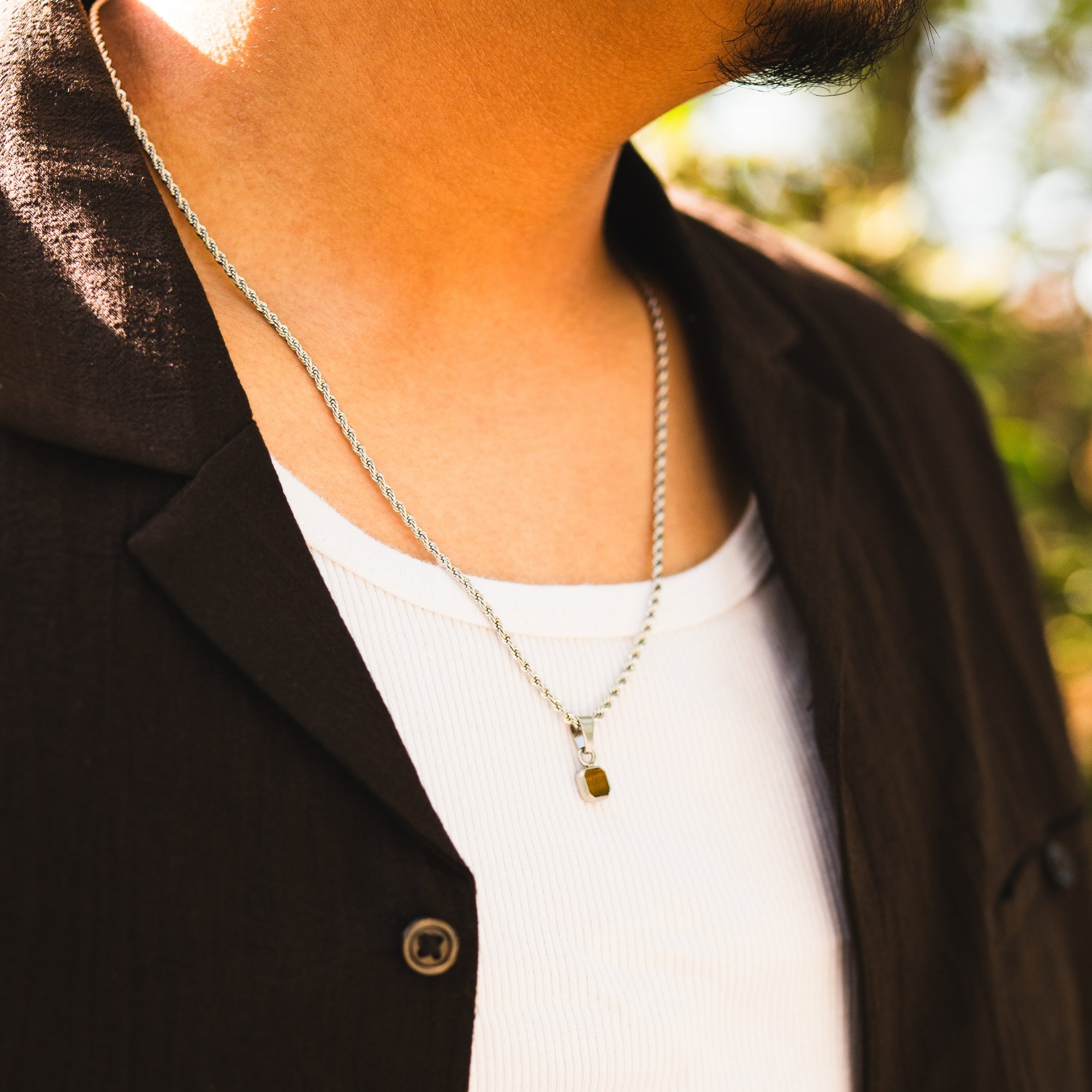 Person wearing a necklace with a blurred outdoor background
