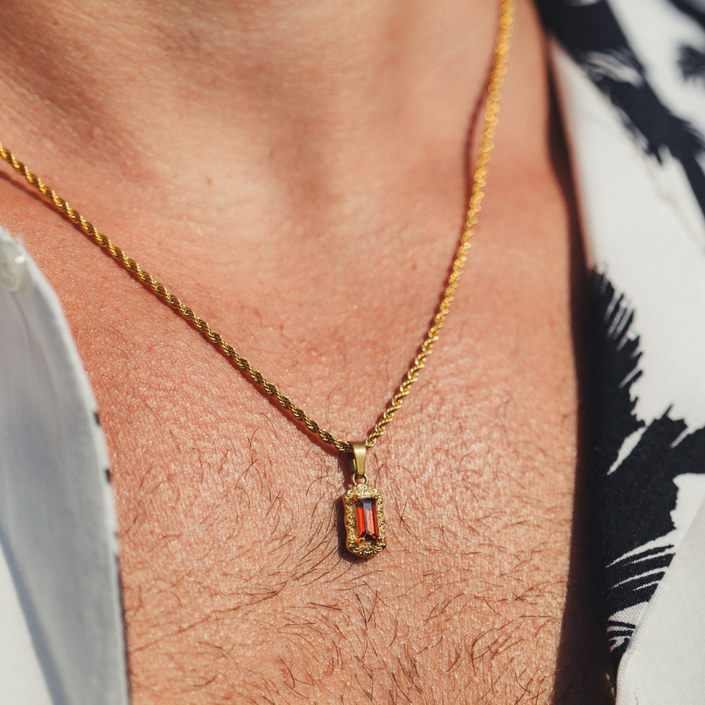Gold necklace with a red gemstone pendant on a person's neck