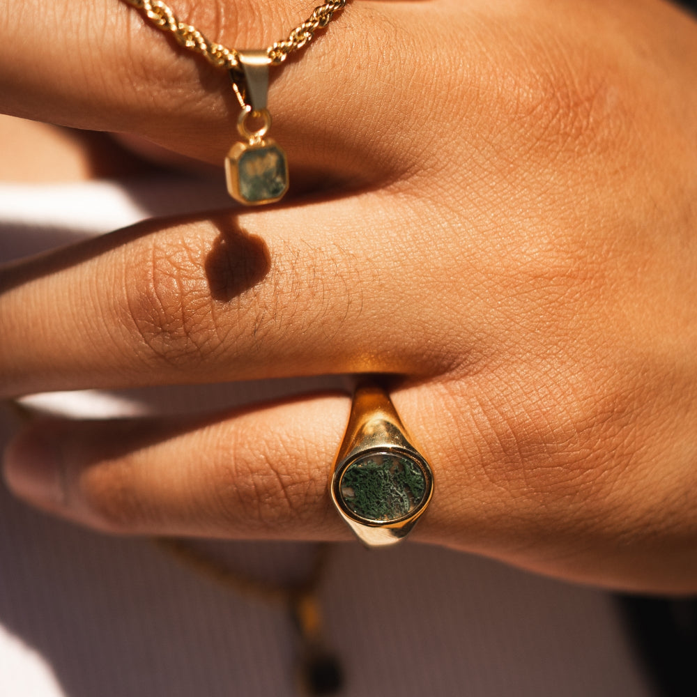 Gold ring with green stone on a hand