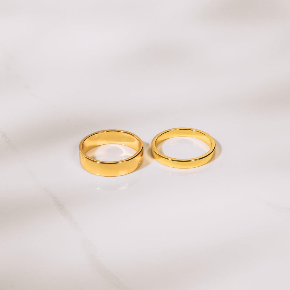 Two gold rings on a light gray background