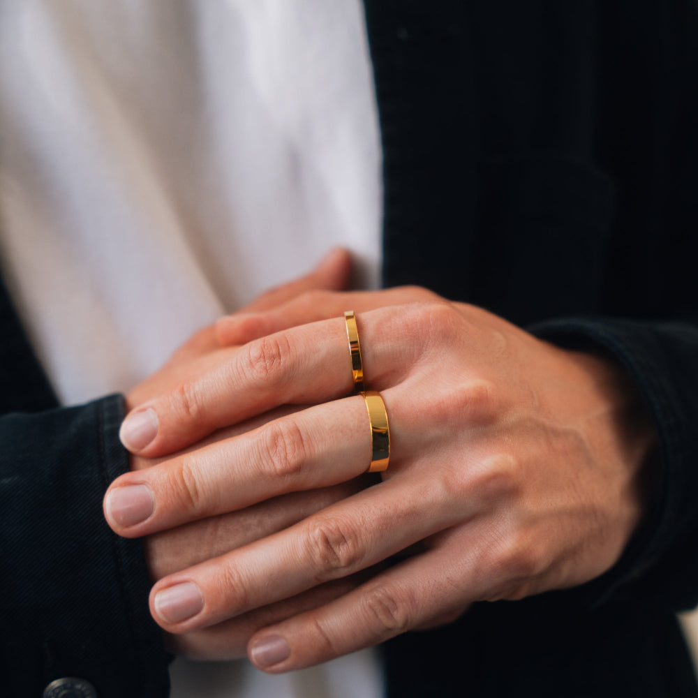 Close-up of hands with gold rings on a neutral background