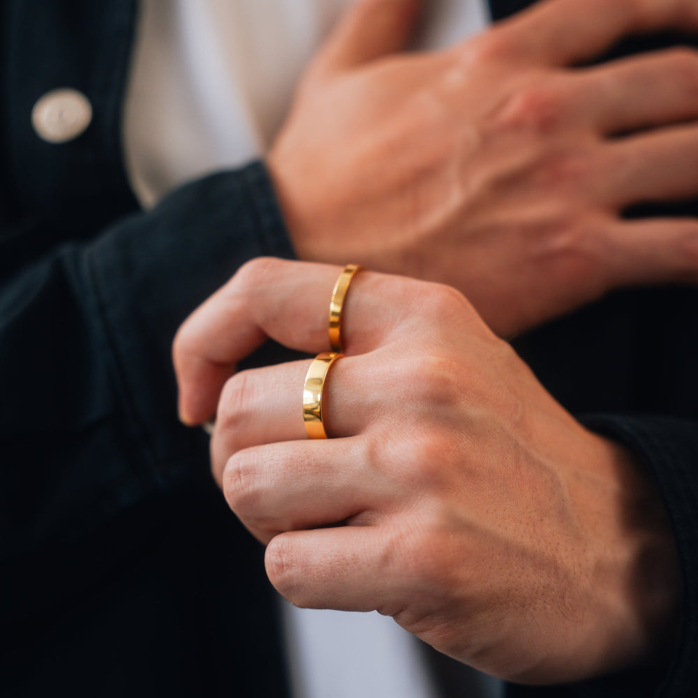 Close-up of a person wearing two gold rings on their fingers.