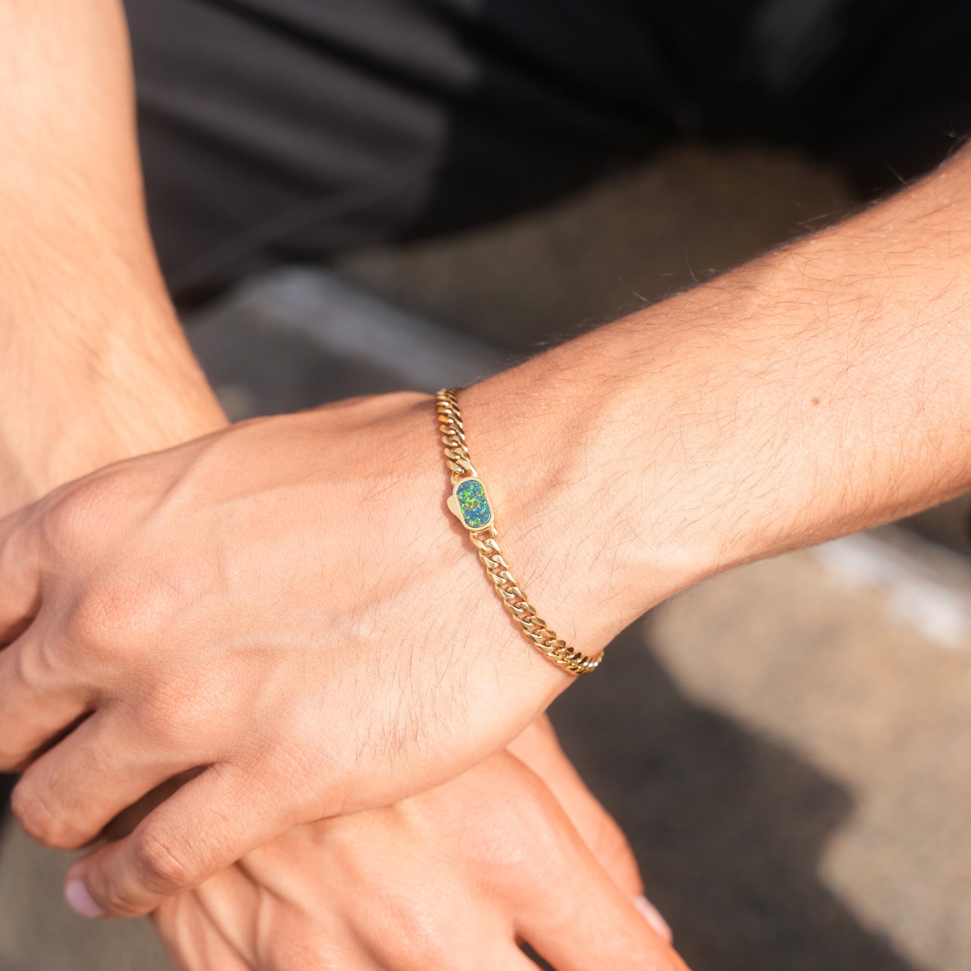 Close-up of a person's wrist wearing a gold bracelet with a green stone.