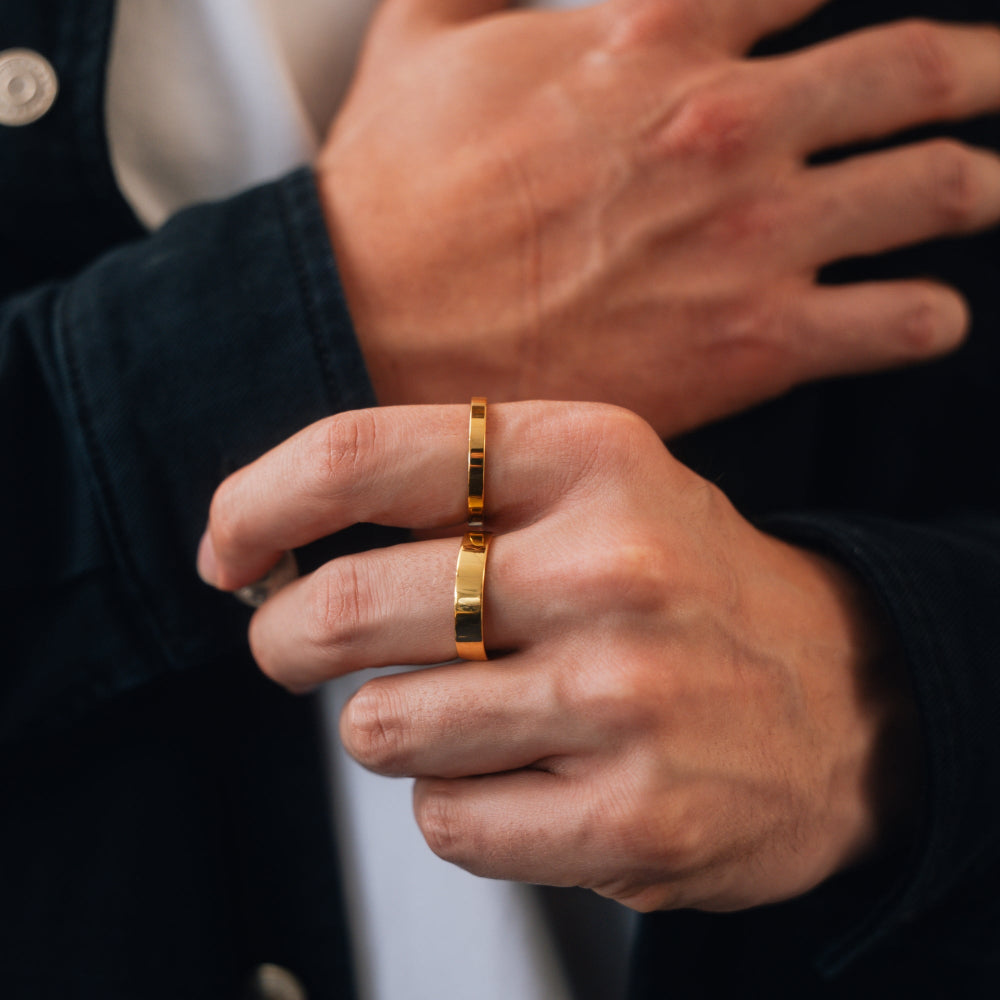 Close-up of a hand wearing a gold ring with a blurred background