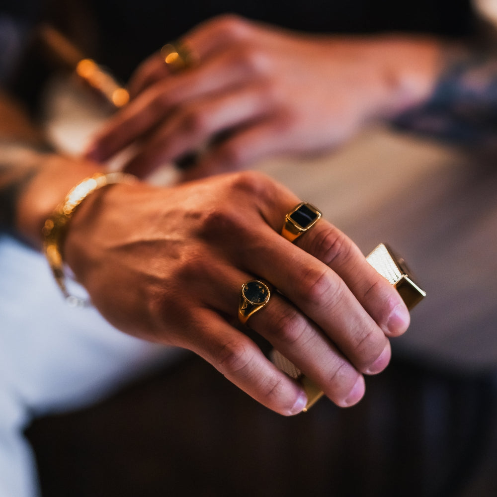 Close-up of hands wearing gold rings on a blurred background