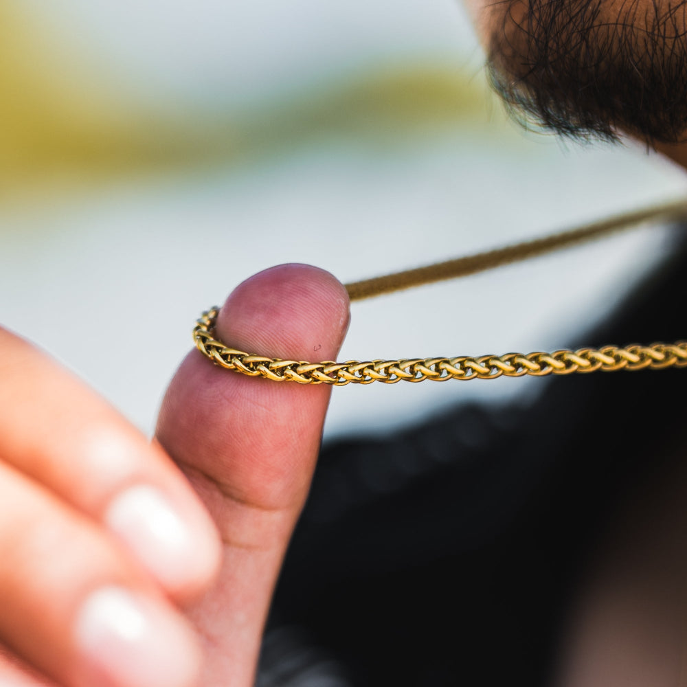 Gold chain held between fingers with a blurred background