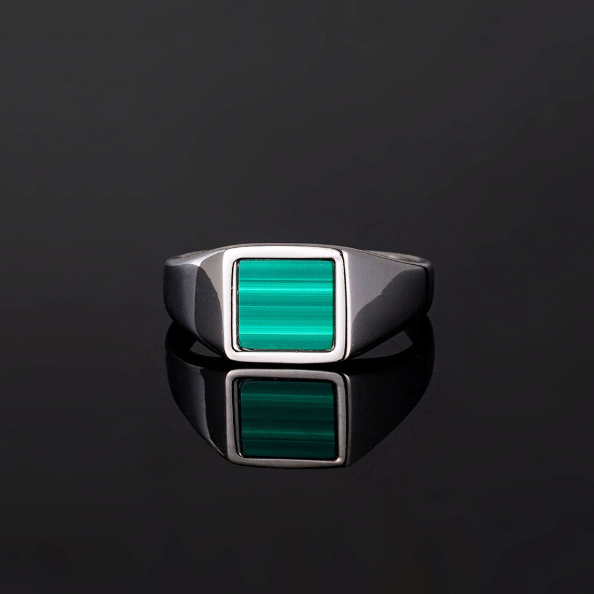 Silver ring with a green stone on a black background