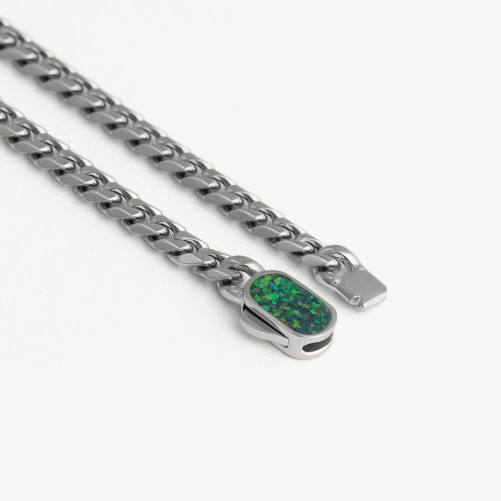 Silver chain necklace with a green pendant on a white background