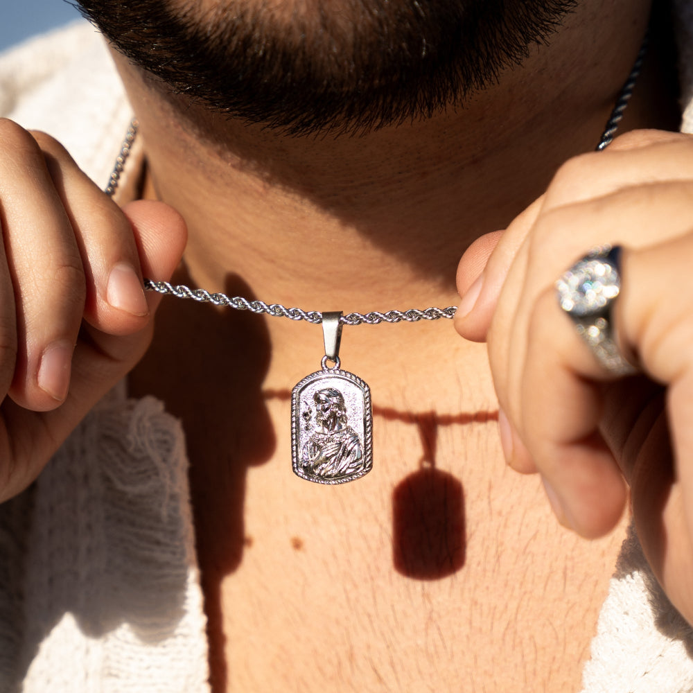 Person holding a silver necklace with a pendant