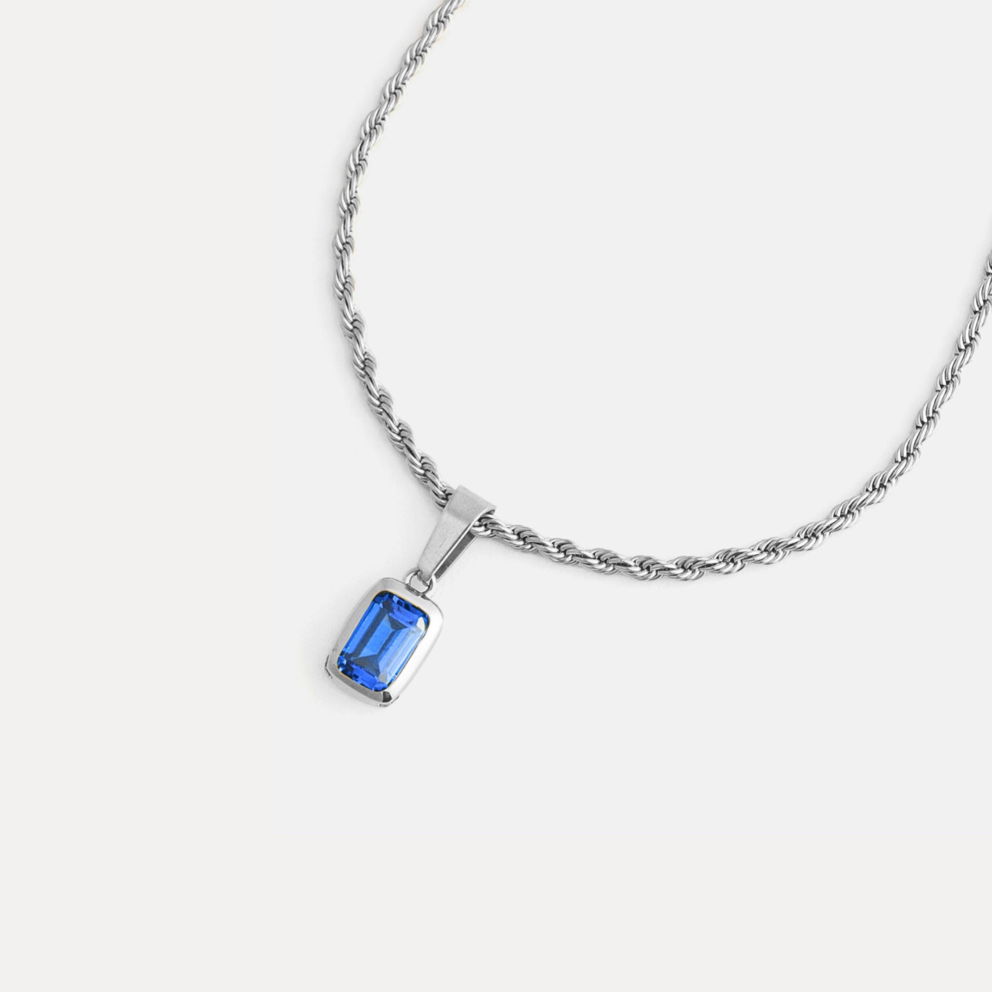 Silver necklace with a blue gemstone pendant on a white background