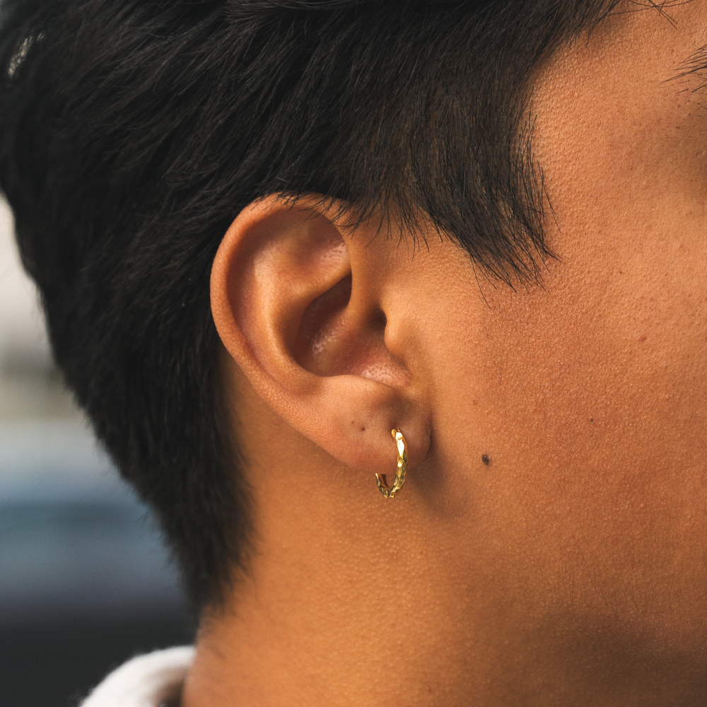 Close-up of a person's ear with a gold hoop earring.