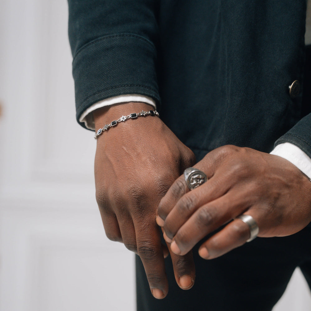 Close-up of a person's hands with rings and a bracelet on a neutral background