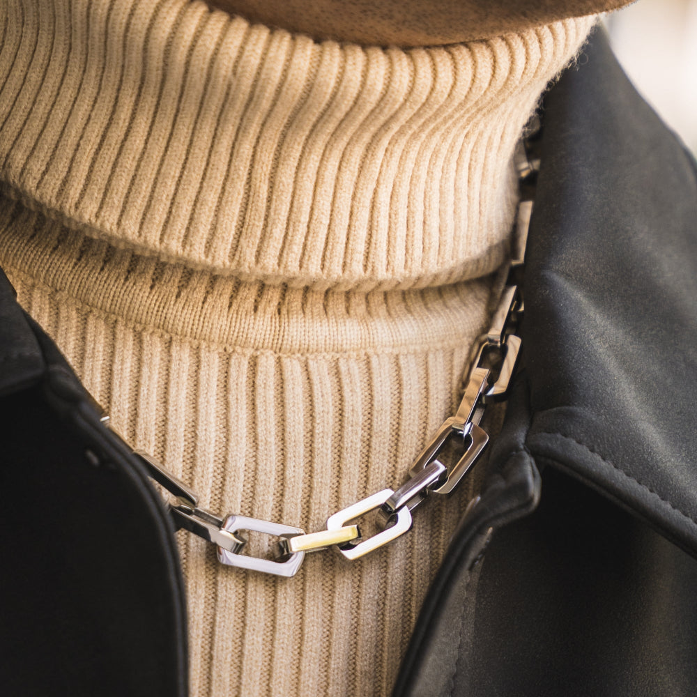 Close-up of a chain belt with a beige sweater and black jacket