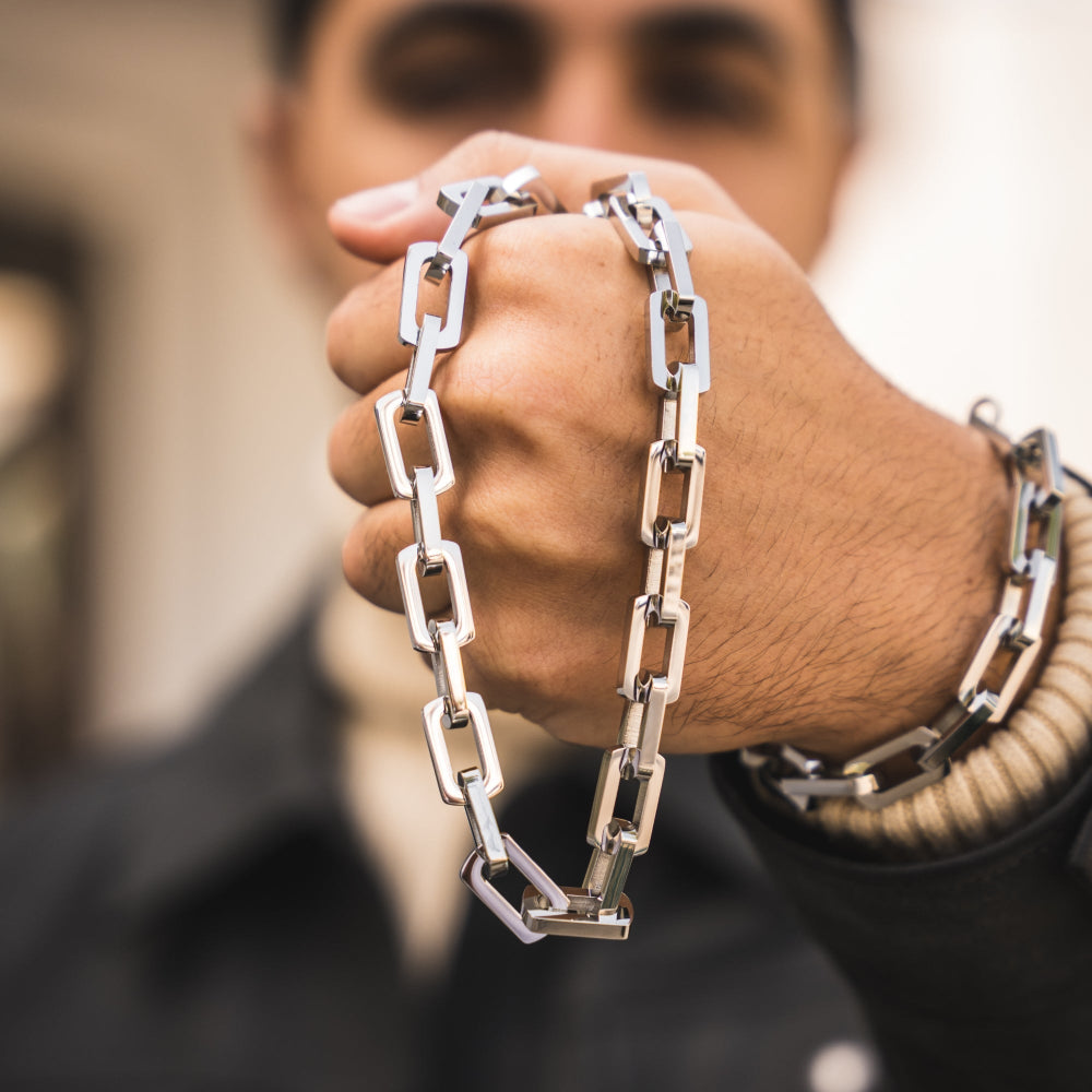 Person wearing a silver chain bracelet on a blurred background