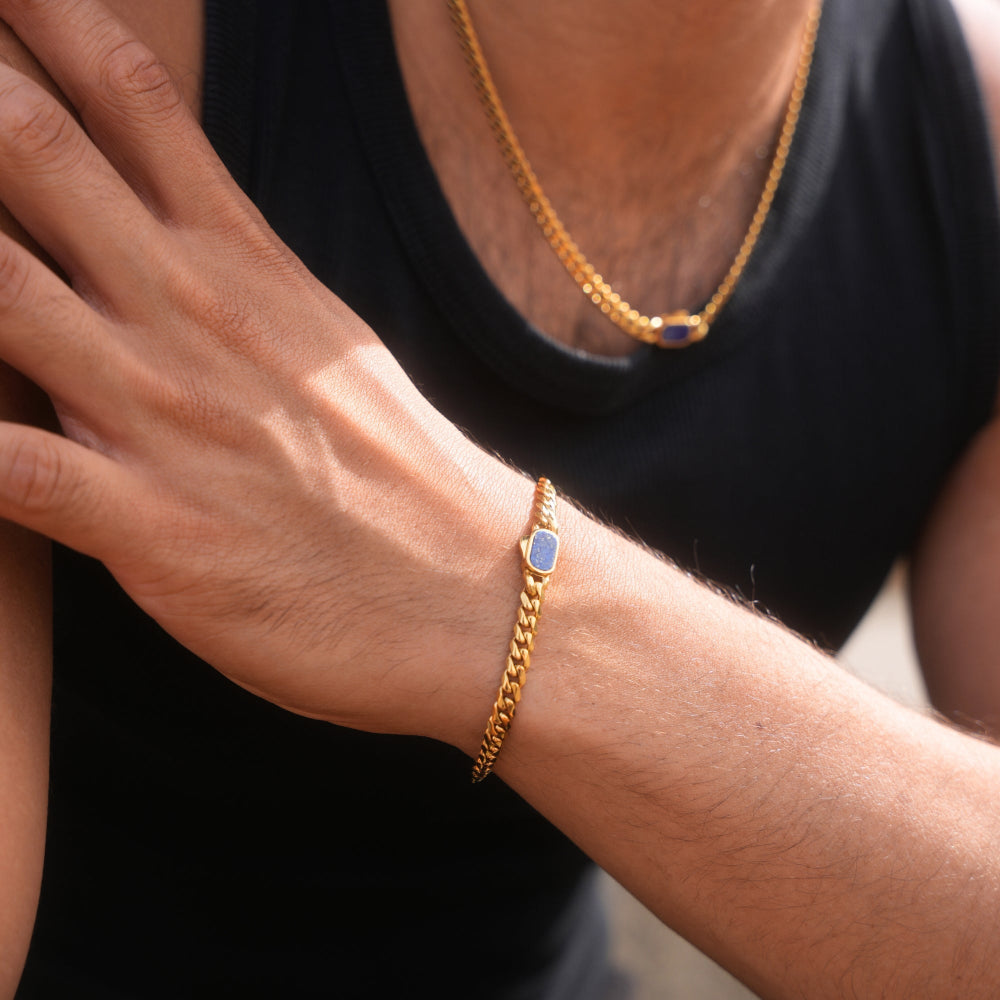 Gold bracelet with a blue stone on a wrist against a black background