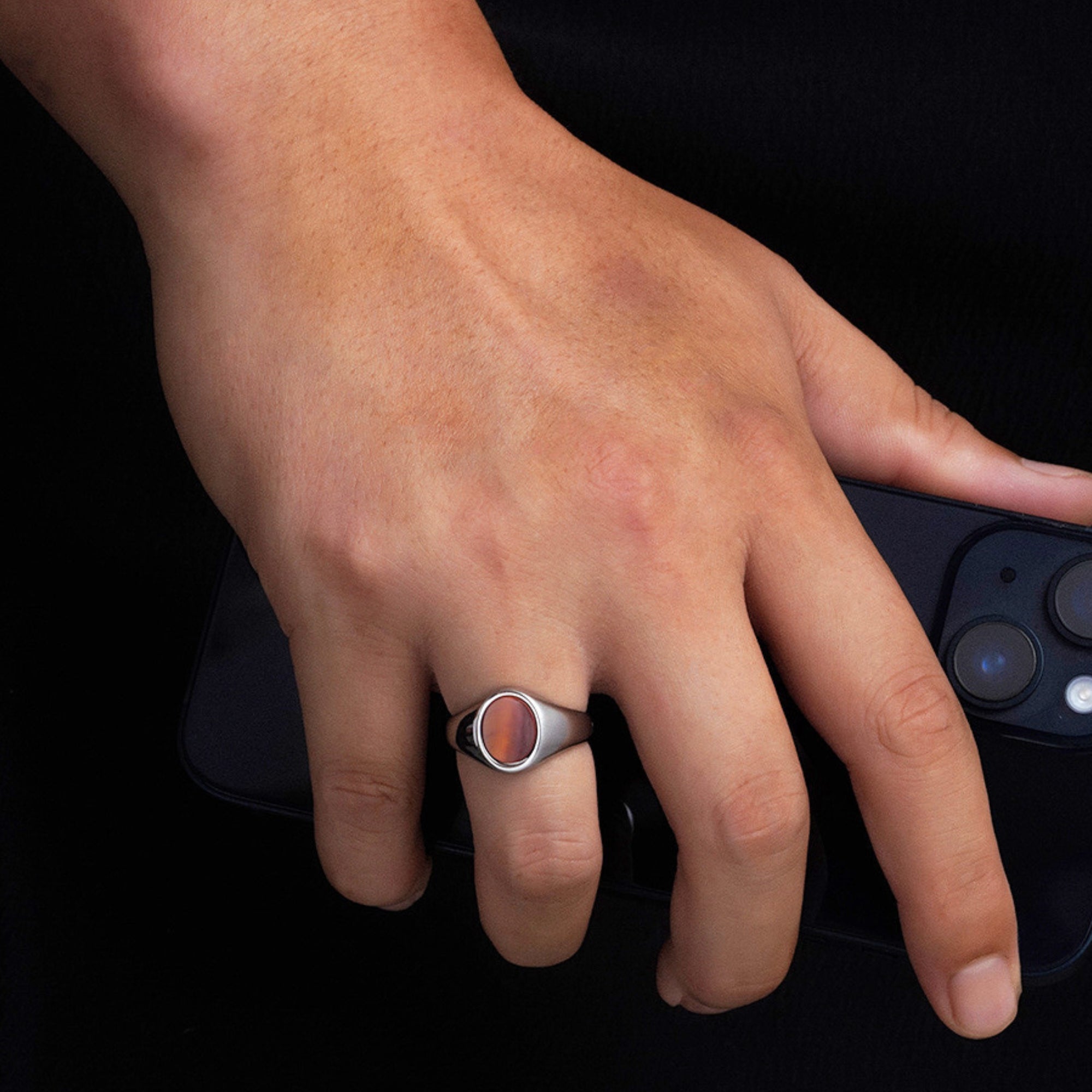 Hand wearing a ring with a dark background