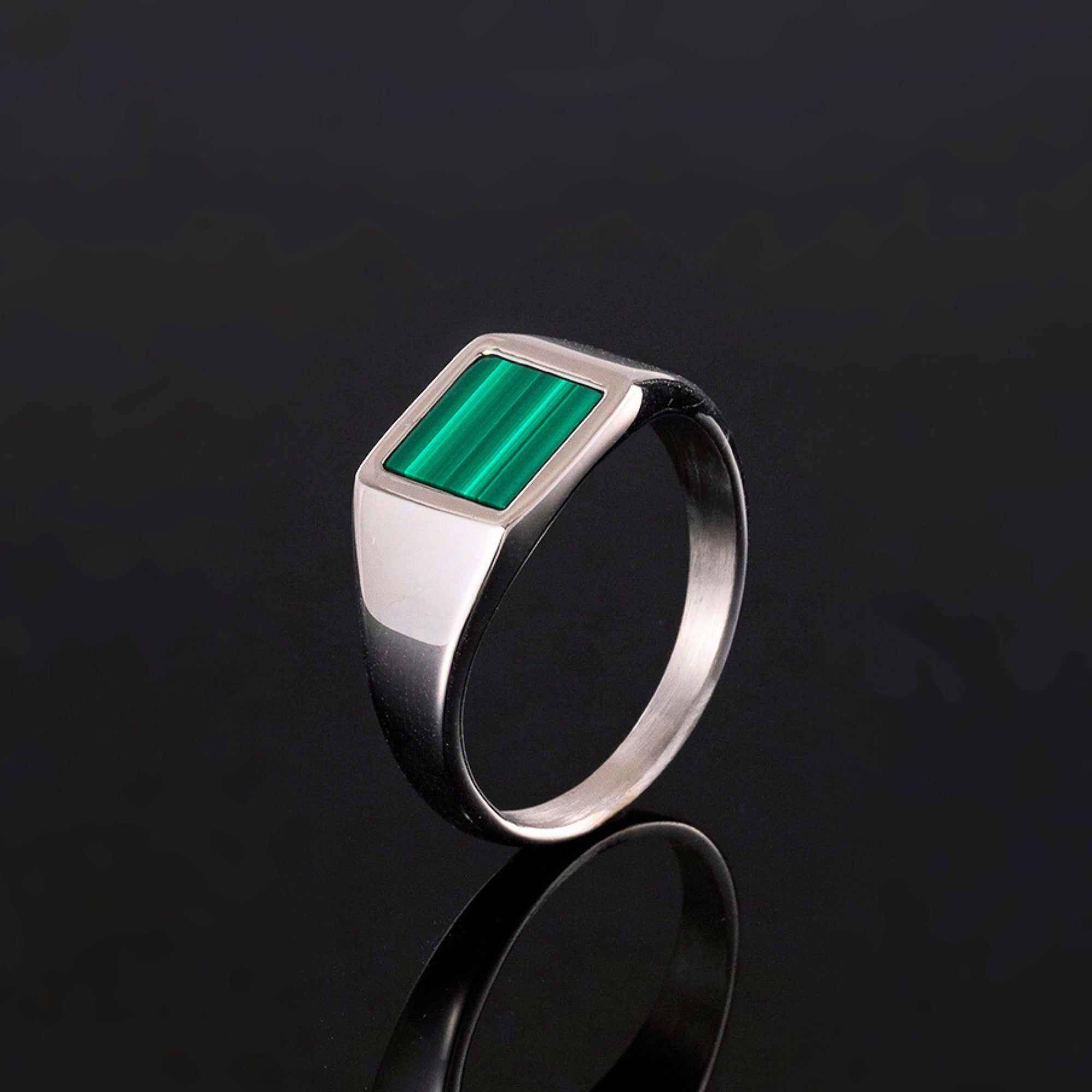 Silver ring with a green stone on a black background