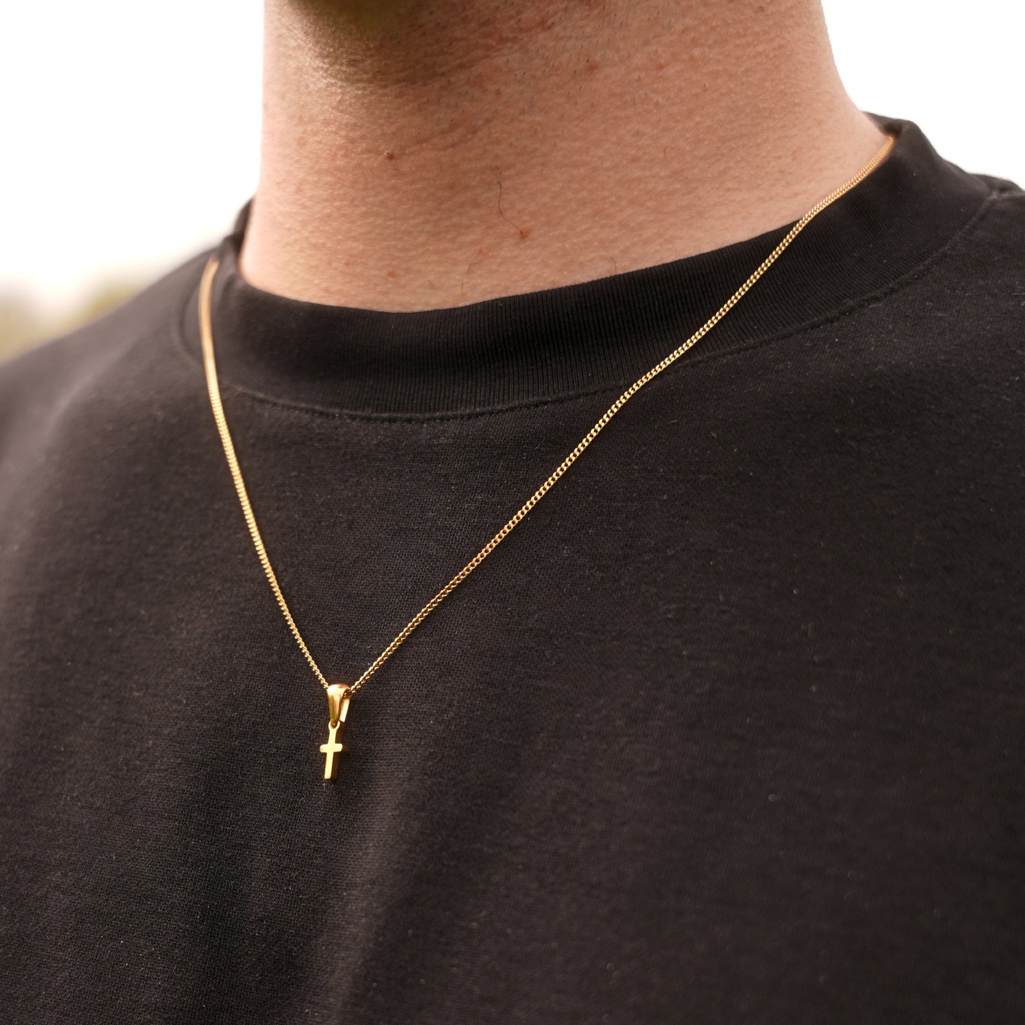 Gold necklace with a cross pendant on a black shirt
