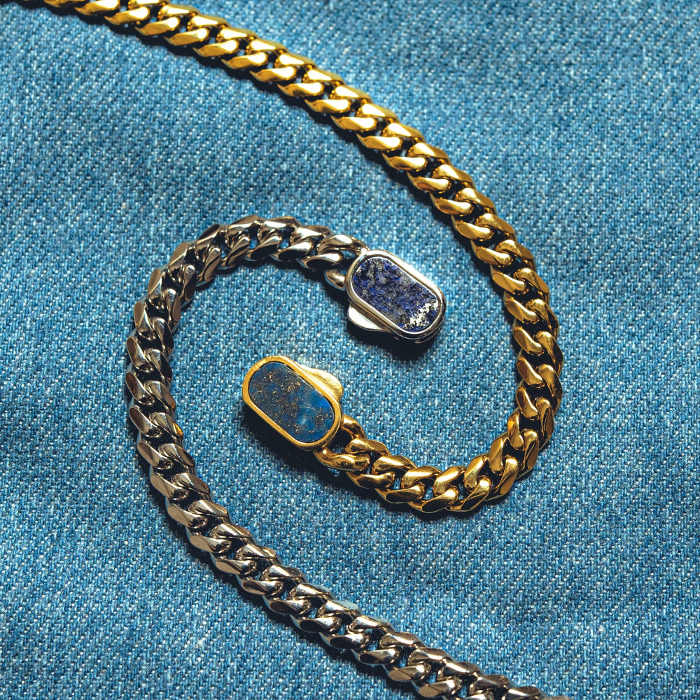 Gold and silver chain with blue stone on a blue fabric background
